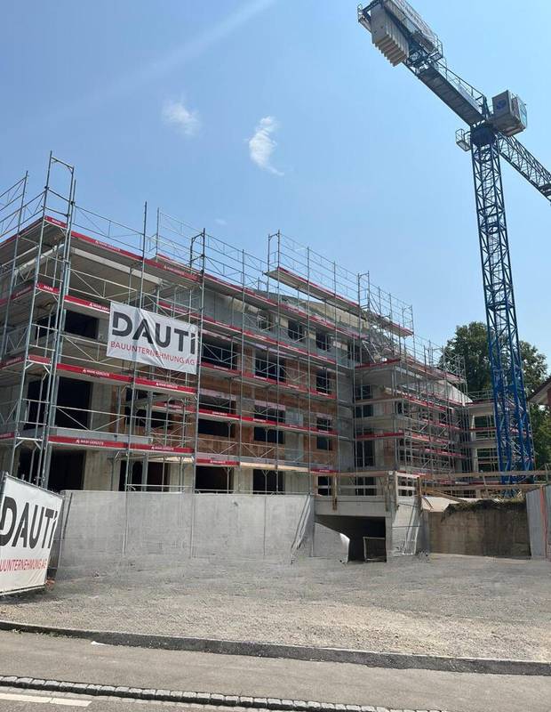 Mehrfamilienhaus im Rohbau mit Gerüst und DAUTI-Banner